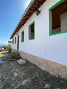 a white building with green windows on it at Pousada Casa Matriz in Itabirito