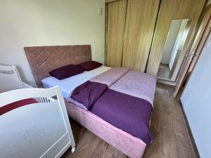 a bedroom with a bed with purple sheets and a mirror at Apartman T&T in Cetinje