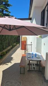 Casa indipendente con giardino privato e posto macchina gratuito في ترييستي: طاولة نزهة مع مظلة وردية ومقعد