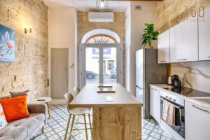 a kitchen with a table and a couch in a room at Stylish Townhouse with Balcony next to Waterfront by 360 Estates in Senglea