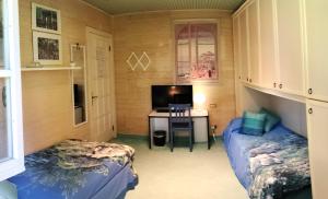 a room with two beds and a desk with a television at B&B Villa Liz Varese in Varese