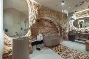 a bathroom with a tub and a brick wall at Nomadic Urban Premium Suites in Krakow
