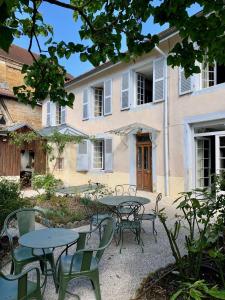 a group of tables and chairs in front of a building at Le Prieuré d'Arbois in Arbois