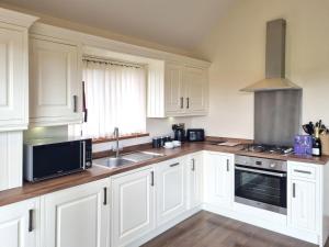 a kitchen with white cabinets and a sink at Maple 14 Hot Tub in Garton +6 photos
