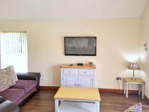 a living room with a couch and a tv on the wall at Maple 14 Hot Tub in Garton