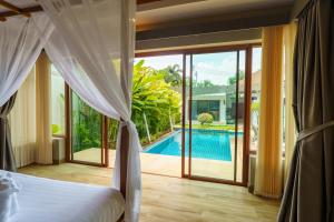 a bedroom with a bed and a view of a pool at Blue Moon by G Estate Phuket in Ban Saiyuan (1)