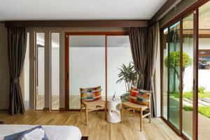 a bedroom with a bed and chairs and a balcony at Blue Moon by G Estate Phuket in Ban Saiyuan (1) +34 photos