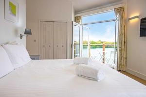 a bedroom with a large white bed and a balcony at The Landings 19, Scout on the Water - P in South Cerney