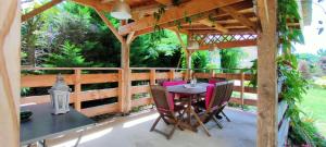 a wooden pergola with a table and chairs on a patio at Gîte La Ferme De Musan in Chatuzange-le-Goubet