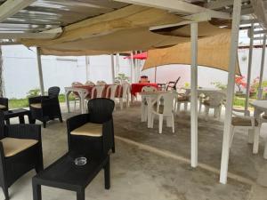 un grupo de mesas y sillas bajo una sombrilla en Maison Mimosa, en Grand-Bassam