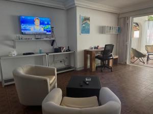 Una sala de estar con un sofá y sillas y un televisor. en Maison Mimosa, en Grand-Bassam