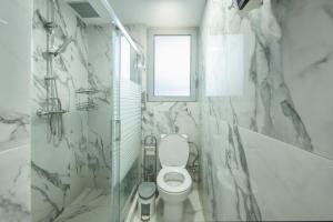 Un baño blanco con inodoro y ventana. en Magical House, en Ialisos 3 fotos más