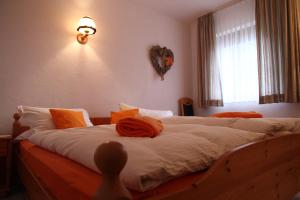 ein Schlafzimmer mit einem großen Bett mit einem orangenen Kissen darauf in der Unterkunft Heidi´s Häuschen in Schollbrunn
