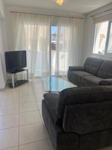 a living room with a couch and a tv at Chara Cynthiana Villa in Paralimni