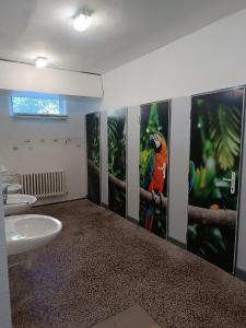 a bathroom with two sinks and a parrot painted on the wall at Chatky na Borovej Sihoti - spoločné wc a sprchy in Podtureň