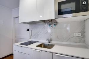 a white kitchen with a sink and a microwave at Compact Chiado Spacious and Exceptional in Lisbon in Lisbon
