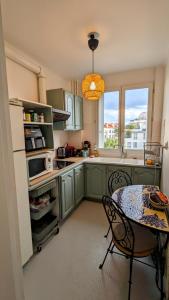 a kitchen with green cabinets and a table and a window at Apt 2 pièces, 2 lits, à 15' Paris centre, 30' Disney in Vincennes