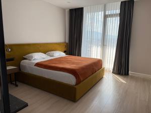 a bedroom with a bed and a large window at Kompleksi Endeta in Bathore +27 photos