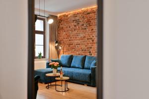 a living room with a blue couch and a brick wall at Szeroka Residences in Toruń