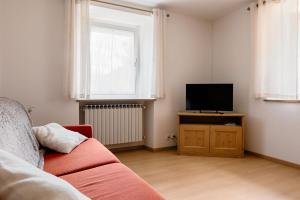 a living room with a red couch and a flat screen tv at Ciasa Silvano 1721 SV in Falcade +11 photos