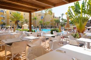 ein Restaurant mit Tischen und Stühlen und ein Swimmingpool in der Unterkunft Sport Hotel Monte Feliz - powered by Playitas in Playa del Aguila