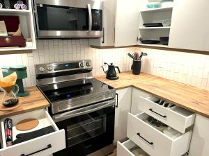 a kitchen with a stove and a microwave at Cedar & Sage Suite - Kitchen & Comfort in Victoria
