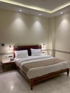 a bedroom with a large bed with white walls at Hotel Anand Bagh -Eraya Hotels in Phulera
