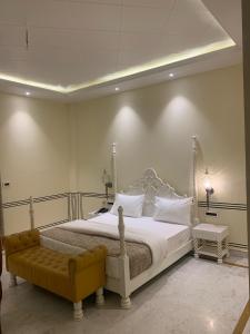 a bedroom with a large white bed with a yellow bench at Hotel Anand Bagh -Eraya Hotels in Phulera