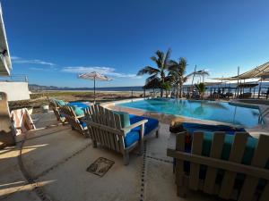 a swimming pool with chairs and a table next to the ocean at Condominio Agave del Mar in Coyuca