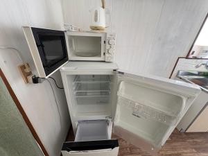 Un refrigerador vacío con la puerta abierta en una cocina. en 木の家ゲストハウス前橋3号館, en Maebashi 12 fotos más
