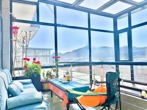 a living room with a couch and a table and windows at Jinshanling Gubeikou Great Wall聚友缘民宿 in Gubeikou