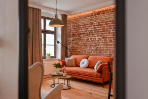a living room with a couch and a brick wall at Szeroka Residences in Toruń