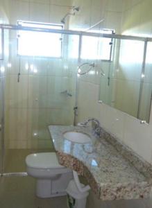 a bathroom with a sink and a toilet and a mirror at Hotel Rezende in Villa Nova de Resende