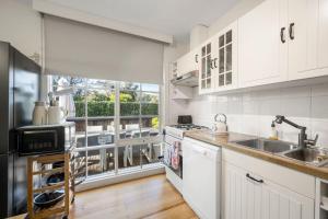ライにあるEpic Group Escape - 900m Walk to Beach!の白いキャビネット、シンク、窓付きのキッチン
