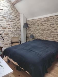 a bedroom with a bed and a brick wall at Les Gîtes des Chaumes de Villeneuve - Le Loft 