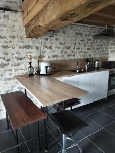 a kitchen with a wooden table and a counter at Les Gîtes des Chaumes de Villeneuve - Le Loft 