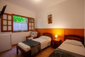 a bedroom with two beds and a chair and a window at Pouso Abaré in Ubatuba
