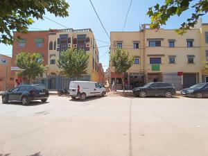 a parking lot with cars parked in front of buildings at Hotel ASSAFIRE in Bou Mia