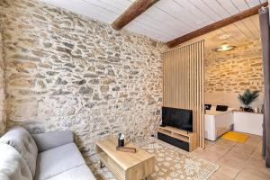 salon z kanapą i kamienną ścianą w obiekcie Jacuzzi de charme pour 2 w mieście Nîmes