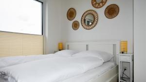 a white bedroom with a large white bed and mirrors at VacationClub - Słoneczne Osiedle Apartament 17 in Ustronie Morskie