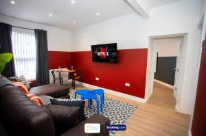a living room with a couch and a red wall at Caxton House Newport by The One Retreats in Newport