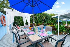 a wooden table with a blue umbrella on a deck at 4br Home W Guest Suite Pool Near Pga & Beach in Palm Beach Gardens