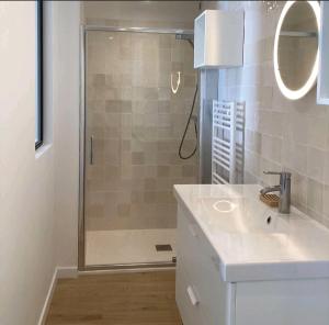 ein Badezimmer mit Dusche, Waschbecken und Spiegel in der Unterkunft AU PIED DE LA MER AU COEUR DE LA STATION bel appartement contemporain in Bénodet