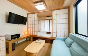 Una sala de estar con un sofá azul y una cama. en We Guest House, en Tokio