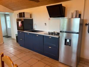 a kitchen with blue cabinets and a stainless steel refrigerator at L ETANG DES VACANCES Maison de charme au cœur des marais pour 6pers in Bouin