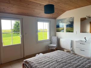 a bedroom with a bed and a chair and windows at L ETANG DES VACANCES Maison de charme au cœur des marais pour 6pers in Bouin +4 photos
