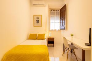 a small bedroom with a bed and a desk at Casa Antares in Granada
