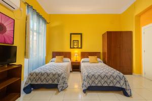 two beds in a room with yellow walls at Casa Antares in Granada +63 photos