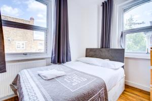 a bedroom with a bed and two windows at Abbey Hotel in London