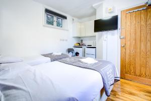 a white bedroom with a bed and a kitchen at Abbey Hotel in London